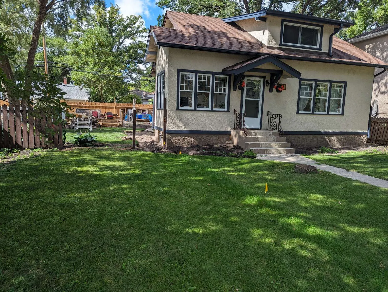 Exterior waterproofing crew sealing foundation wall during summer